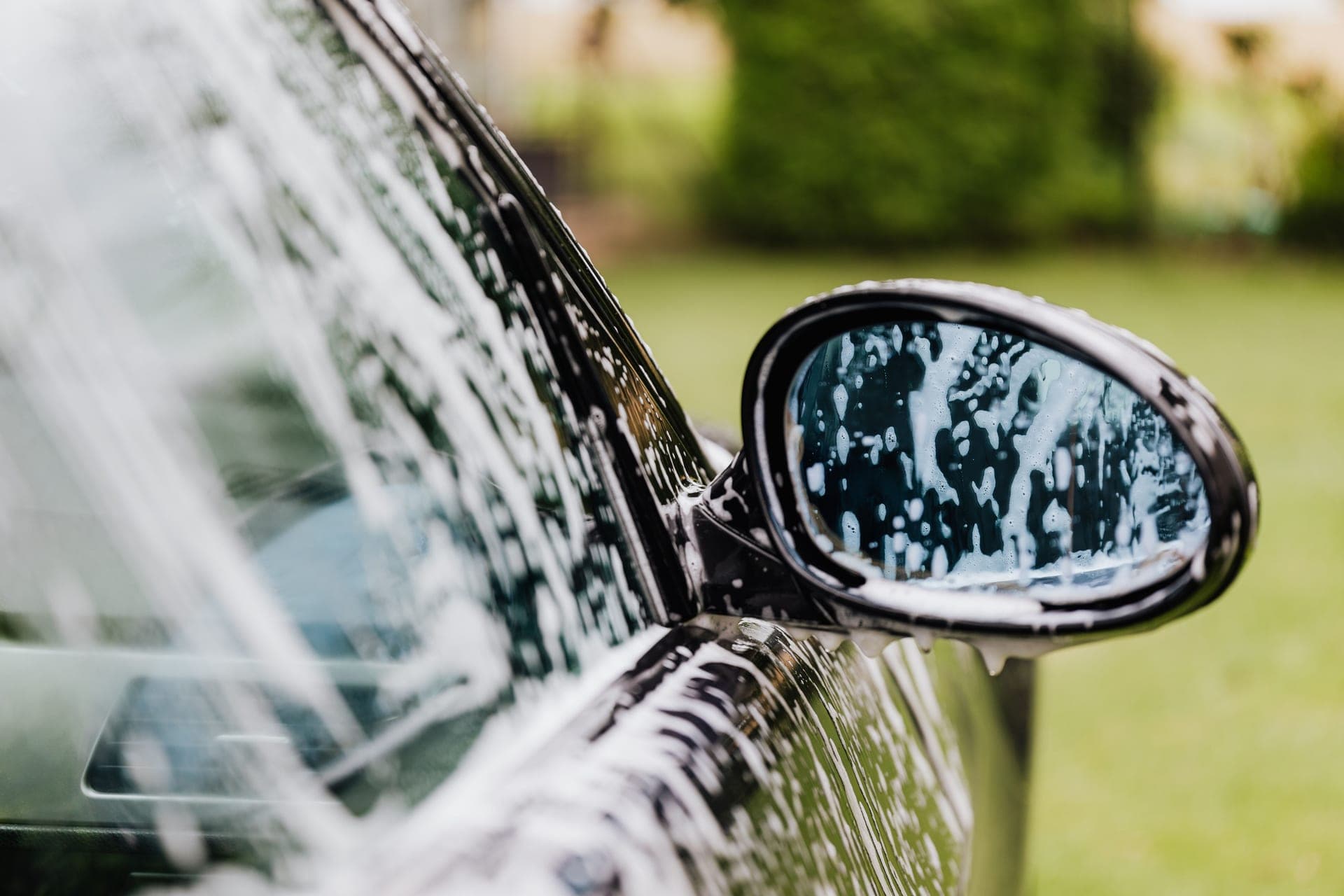 A car being washed with thick foam and water under directional light